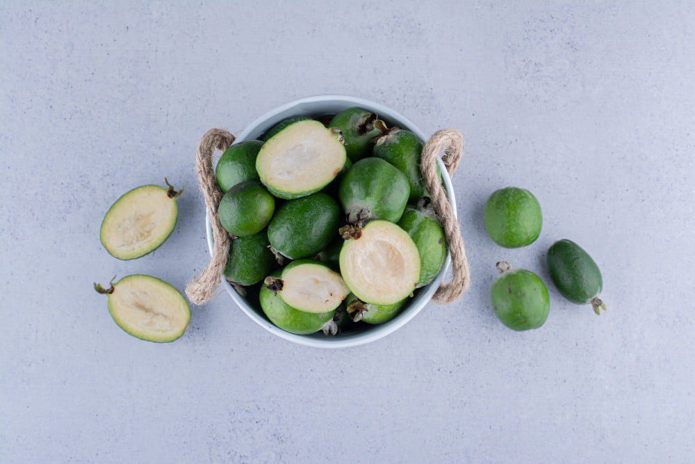 Freshly harvested feijoas cut in half showing the creamy white flesh inside